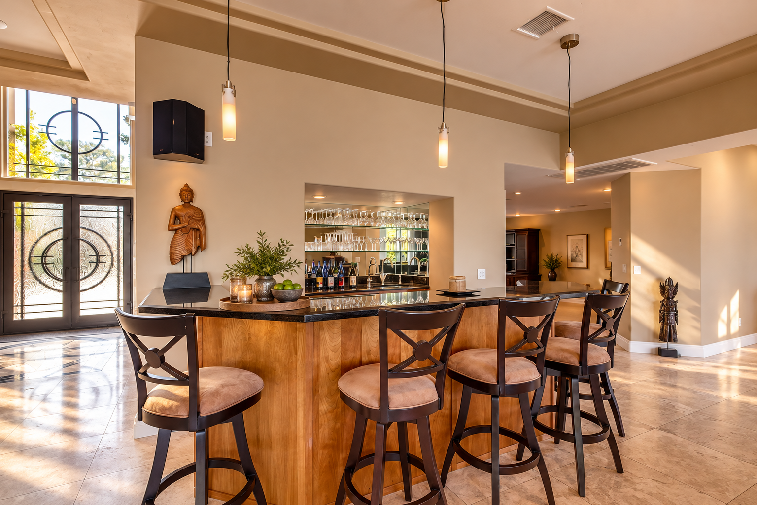 Indoor bar with seating, glassware and a carved Buddha beside the entry doors at Oasis